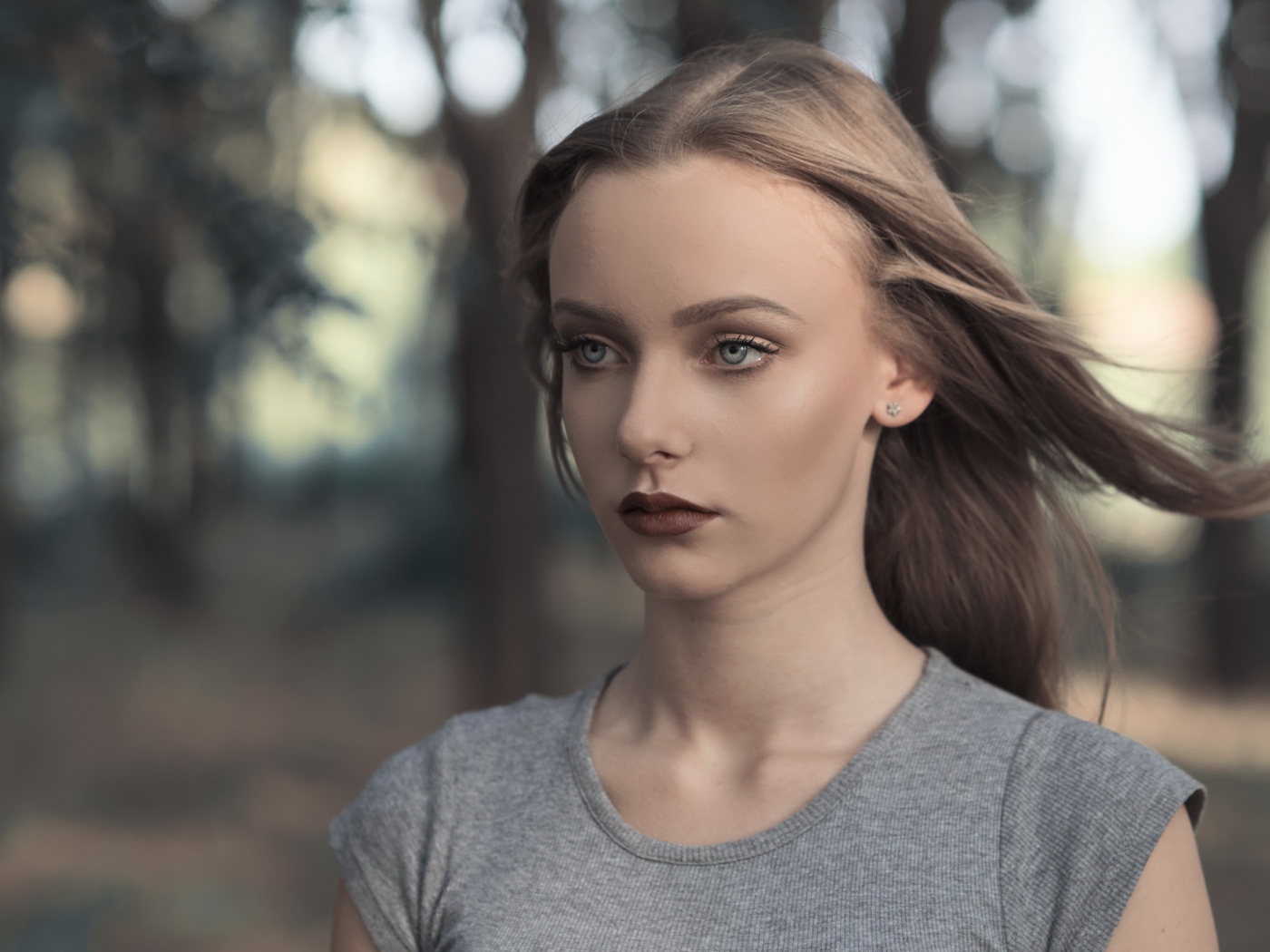 Голубоглазая девушка в серой майке в парке 