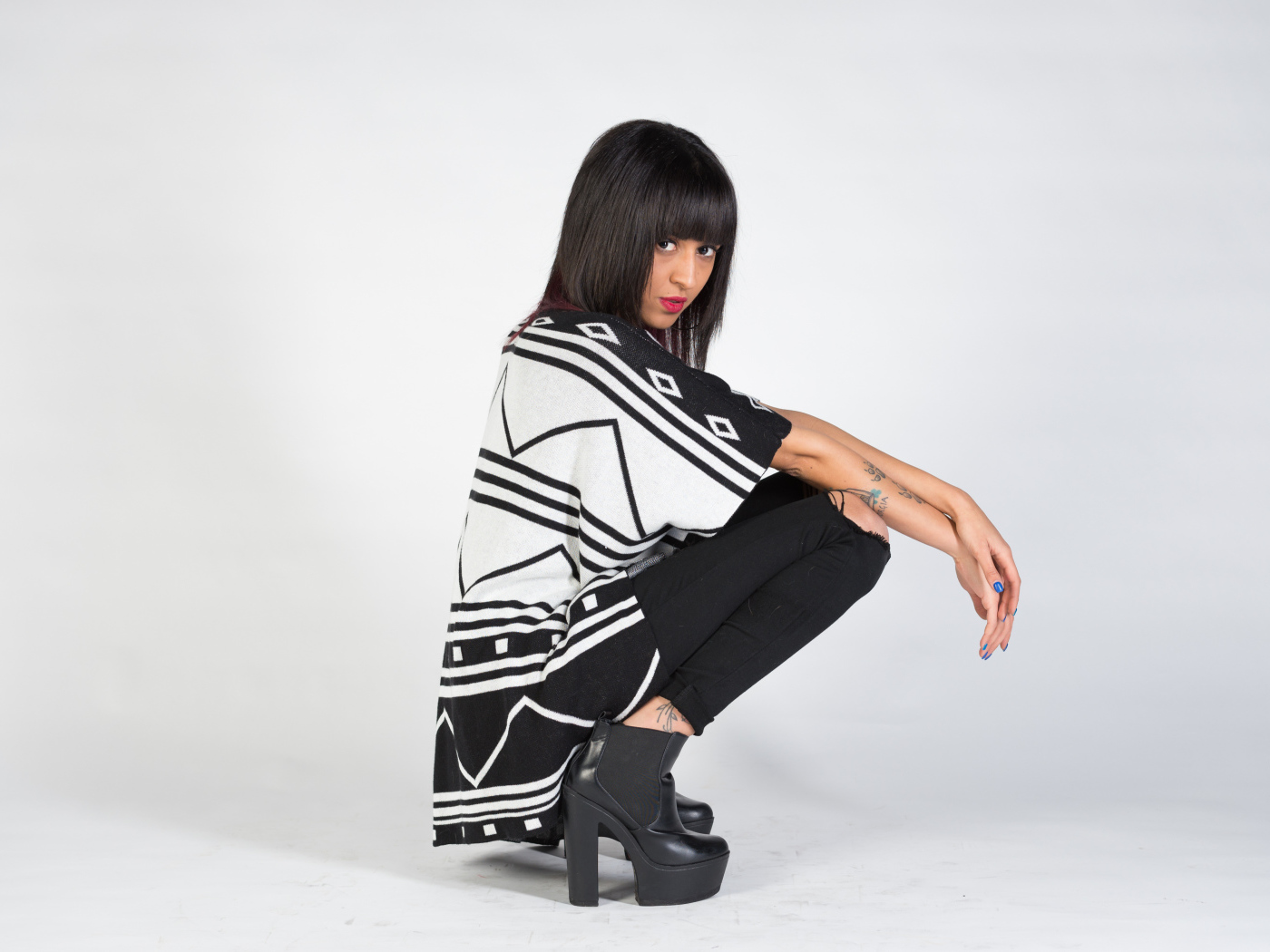 Брюнетка сидит на корточках 