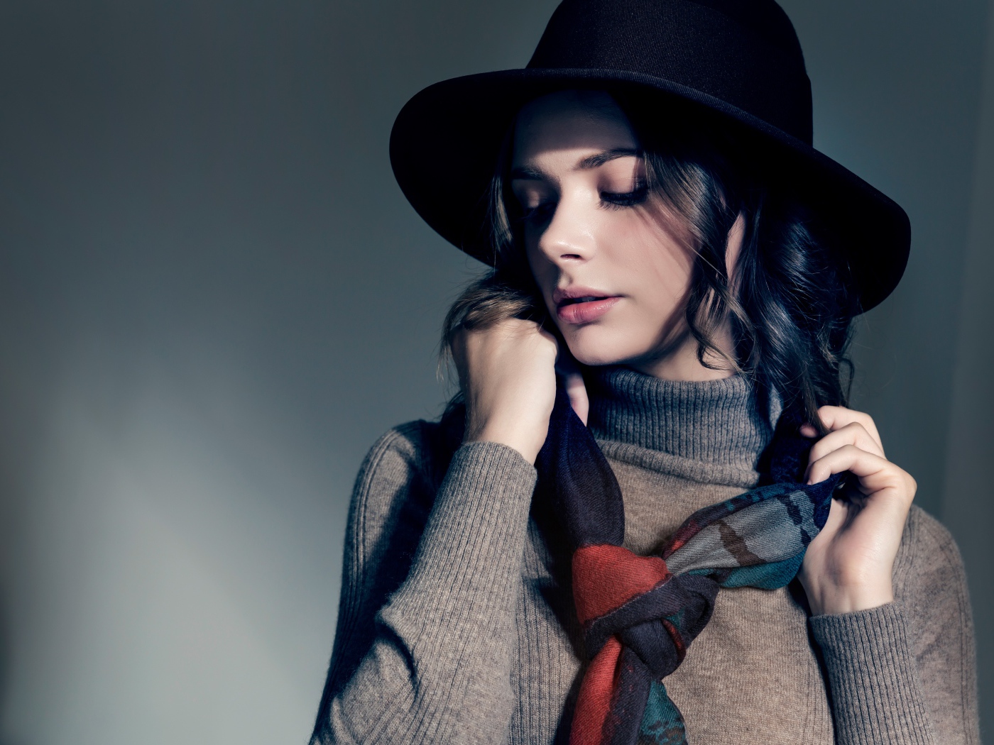 Девушка в сером свитере с платком на шее в черной шляпе