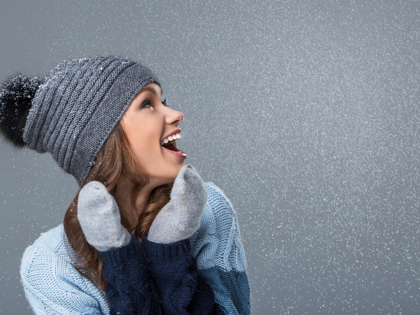 Девушка в теплой шапке на сером фоне