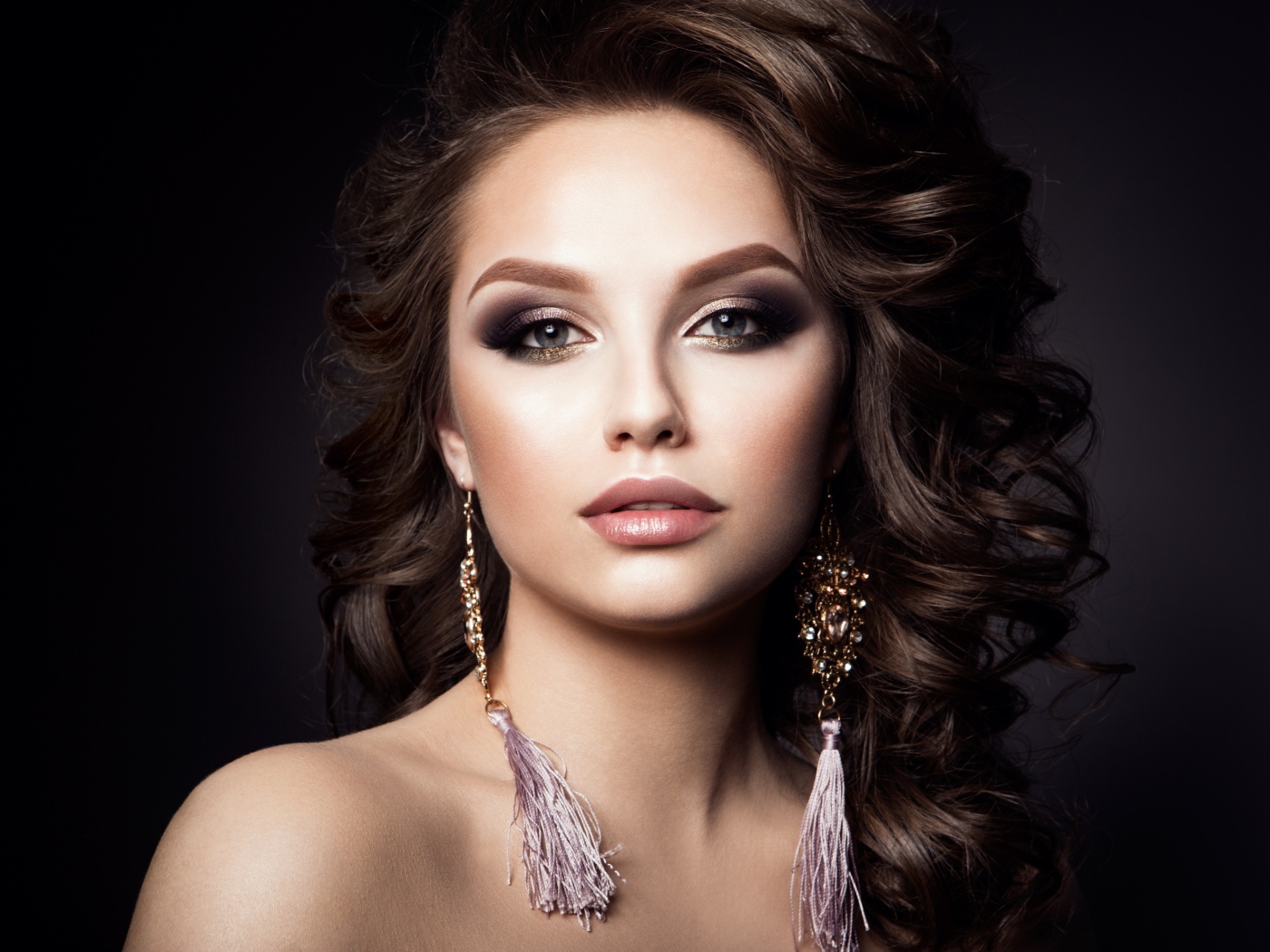 Девушка с прической с красивыми сережками на сером фоне 