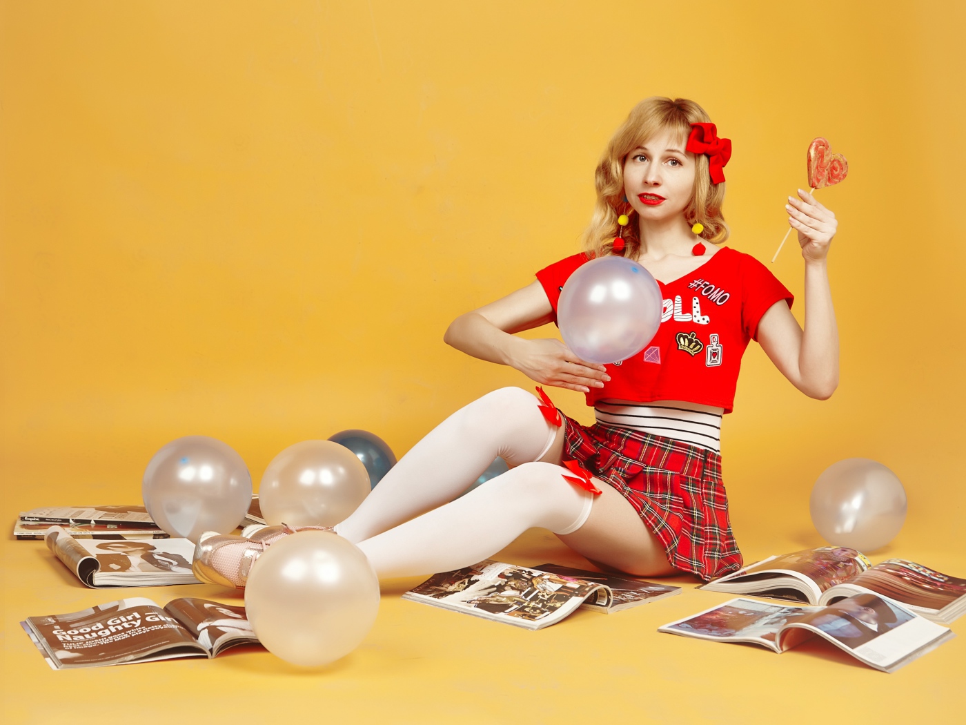 Девушка с шариками и журналами сидит на полу