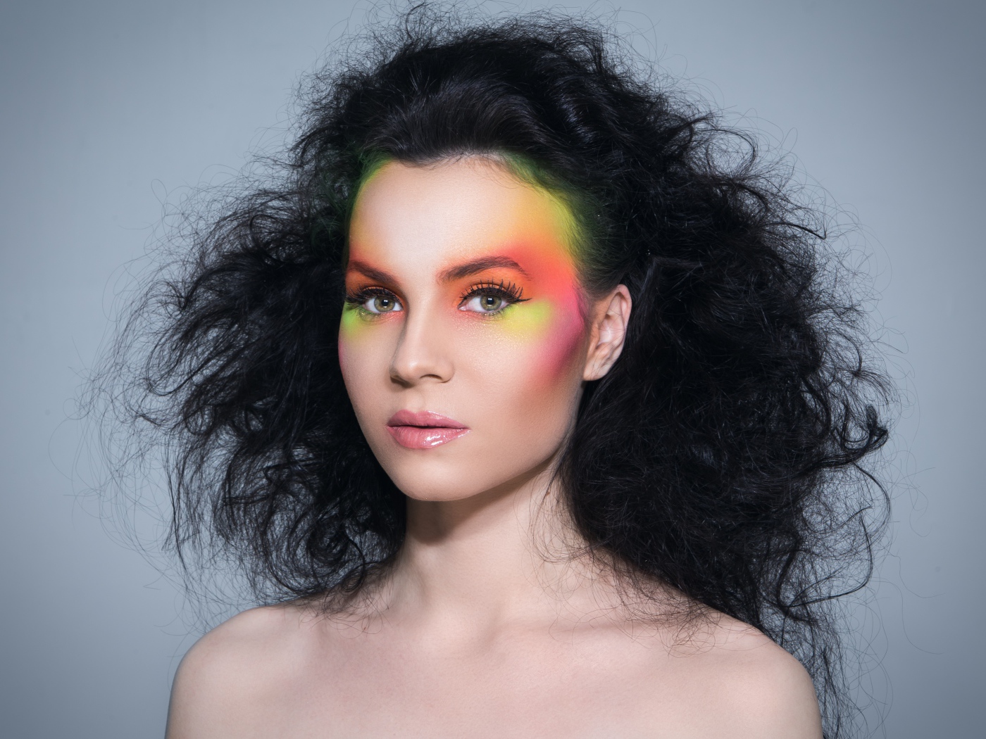 Девушка с начесом на волосах с ярким макияжем на сером фоне