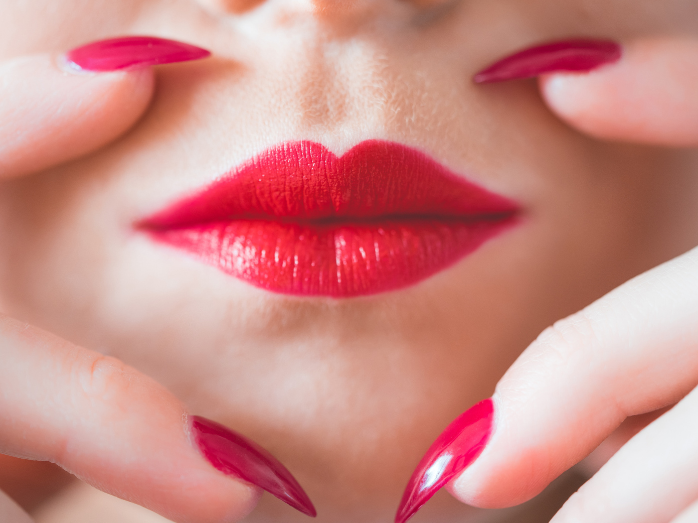 Руки с длинными красными ногтями у губ