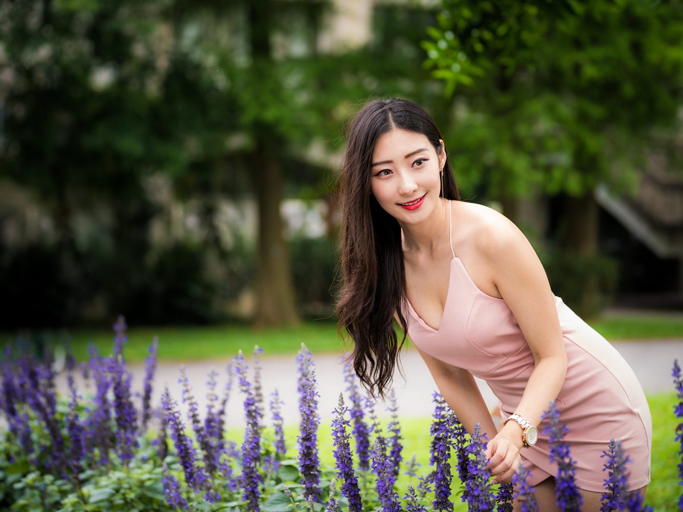 Милая девушка Азиатка в розовом платье у синих цветов