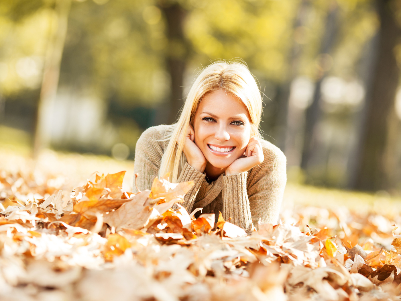 Улыбающаяся девушка лежит на сухой опавшей листве