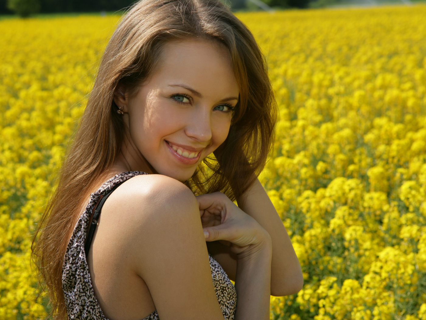 Улыбающаяся девушка на фоне поля с желтыми цветами