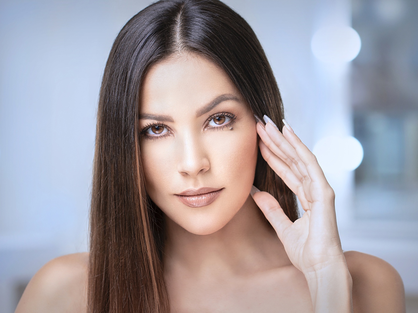 Стильная кареглазая длинноволосая брюнетка с рукой у лица