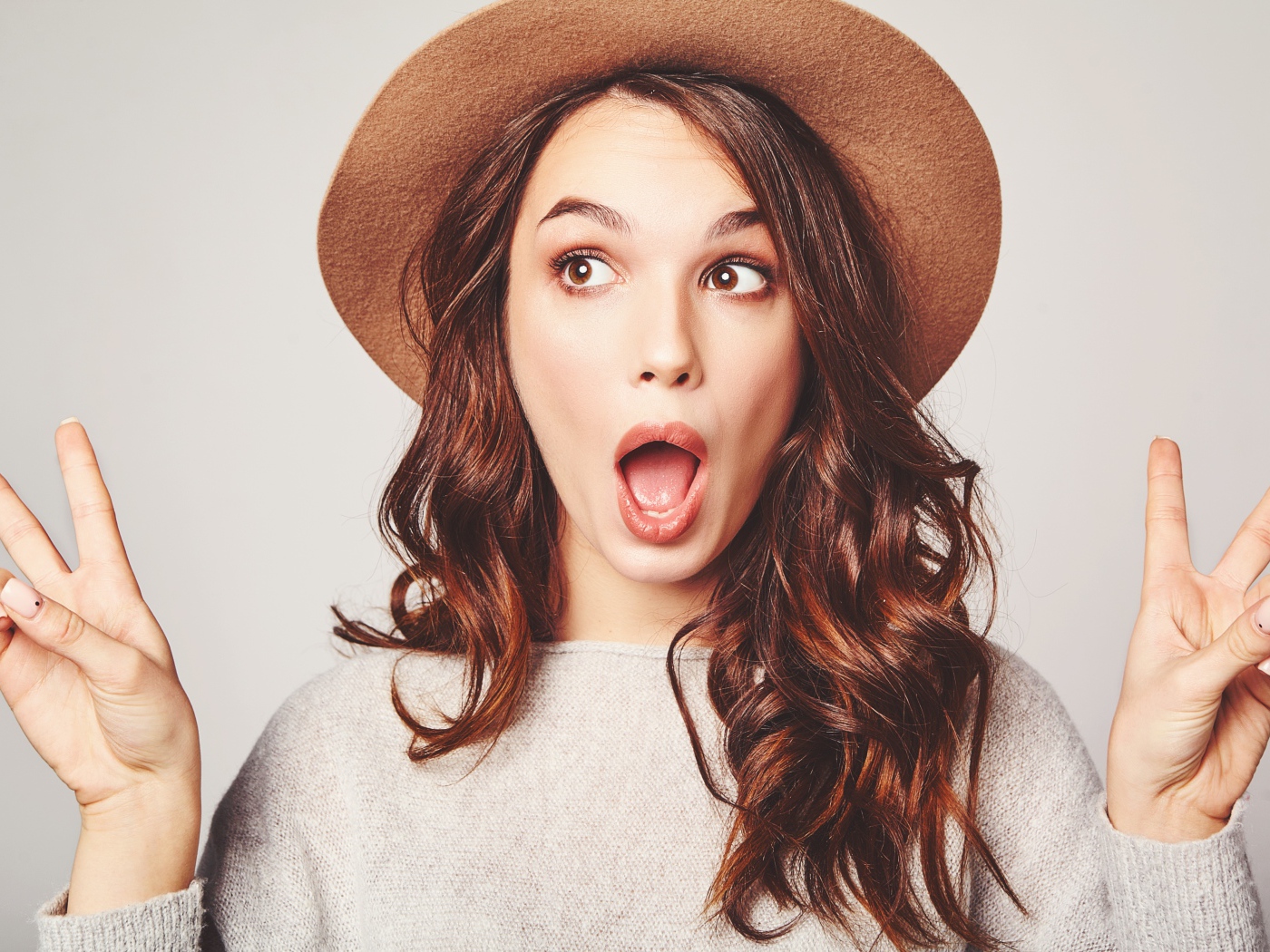 Удивленная девушка с длинными волосами в коричневой шляпе 