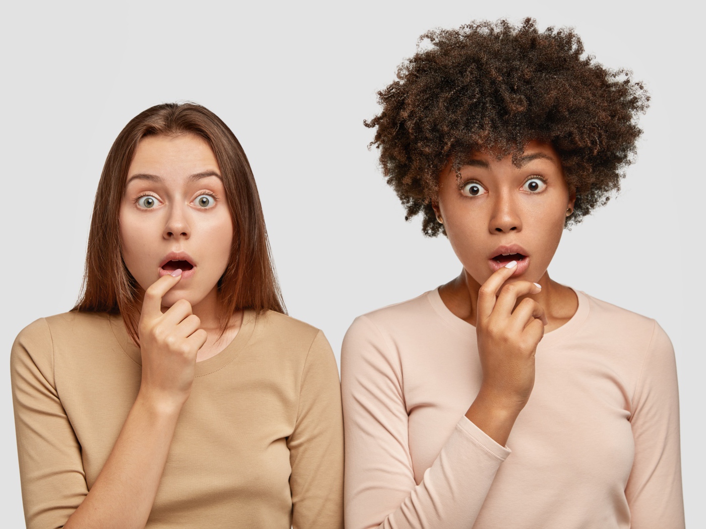 Две удивленные девушки на сером фоне 