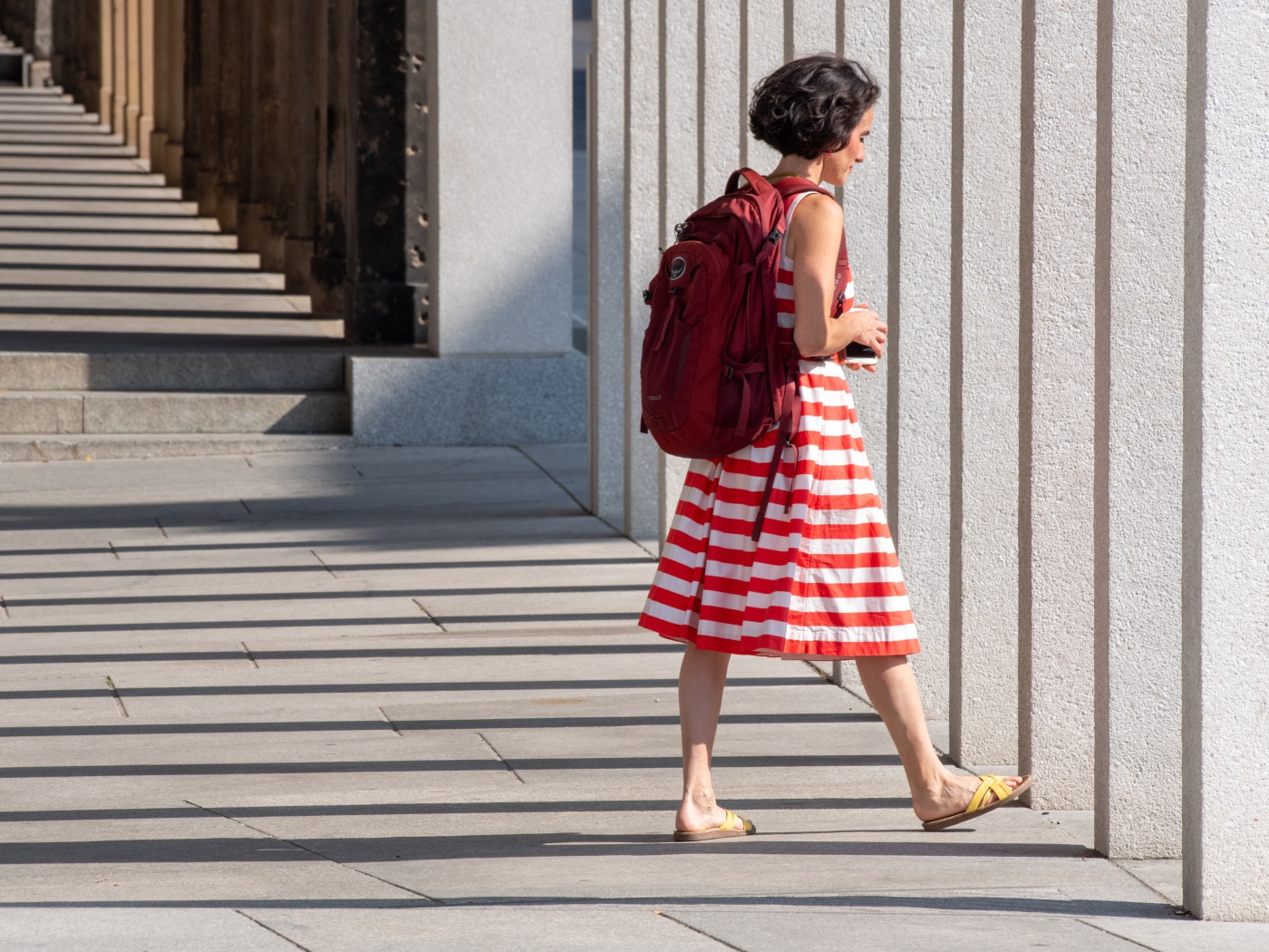 Женщина в красном полосатом платье с рюкзаком