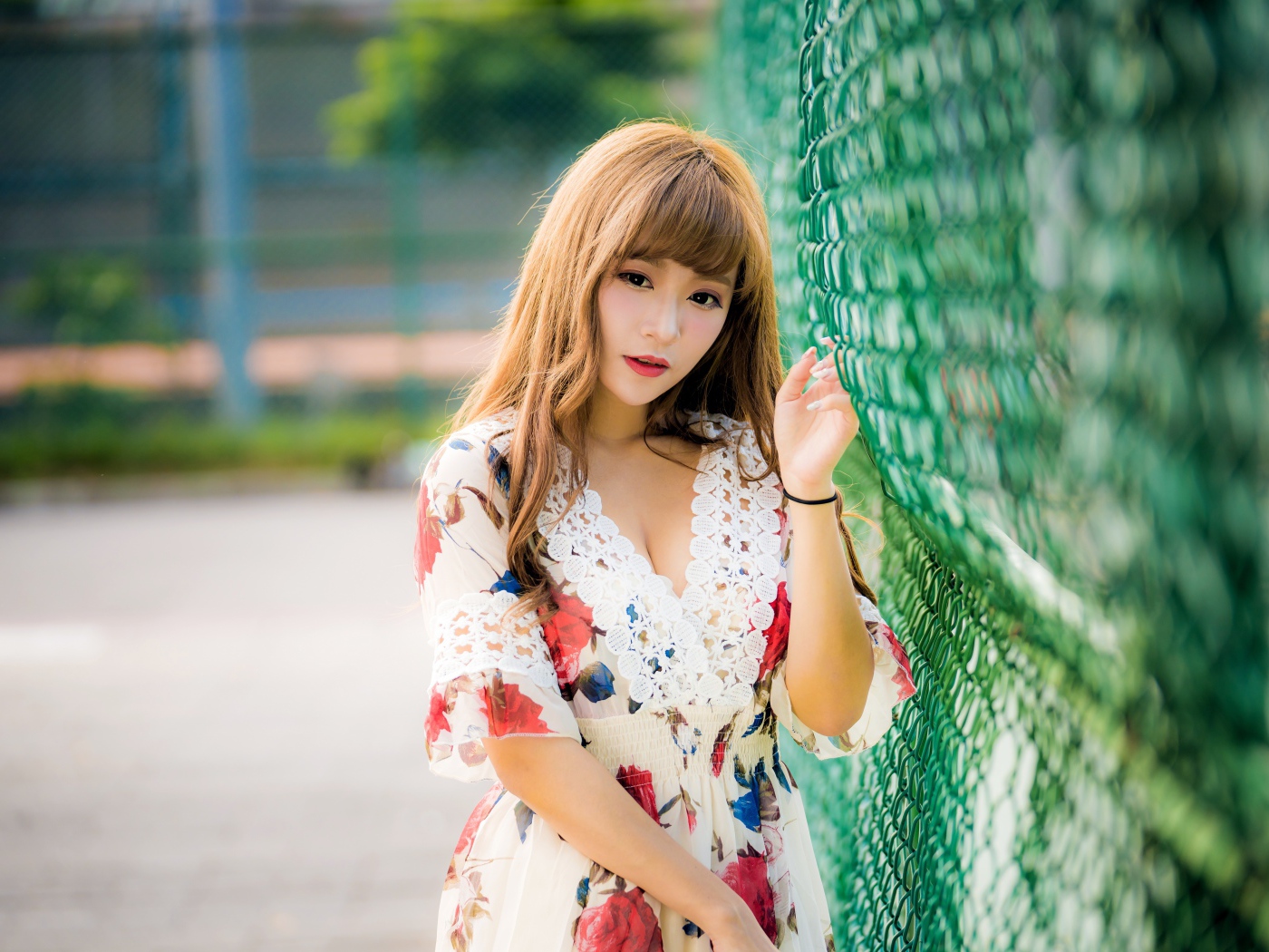 Молодая азиатка в платье у зеленой сетке 