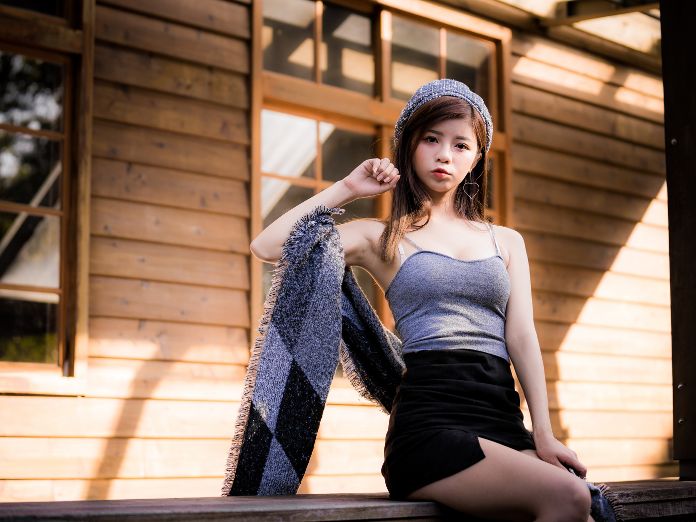 Молодая девушка азиатка в короткой юбке сидит на подоконнике 