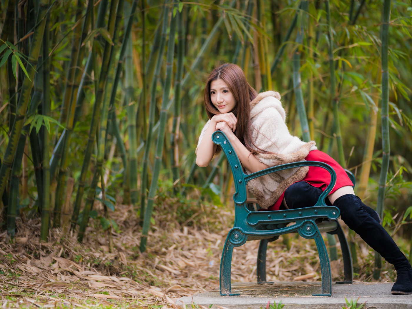 Молодая девушка азиатка сидит на зеленой лавке 