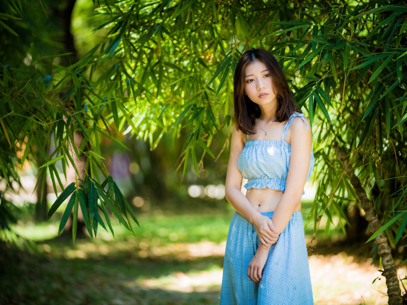 Молодая девушка в голубом костюме под деревом