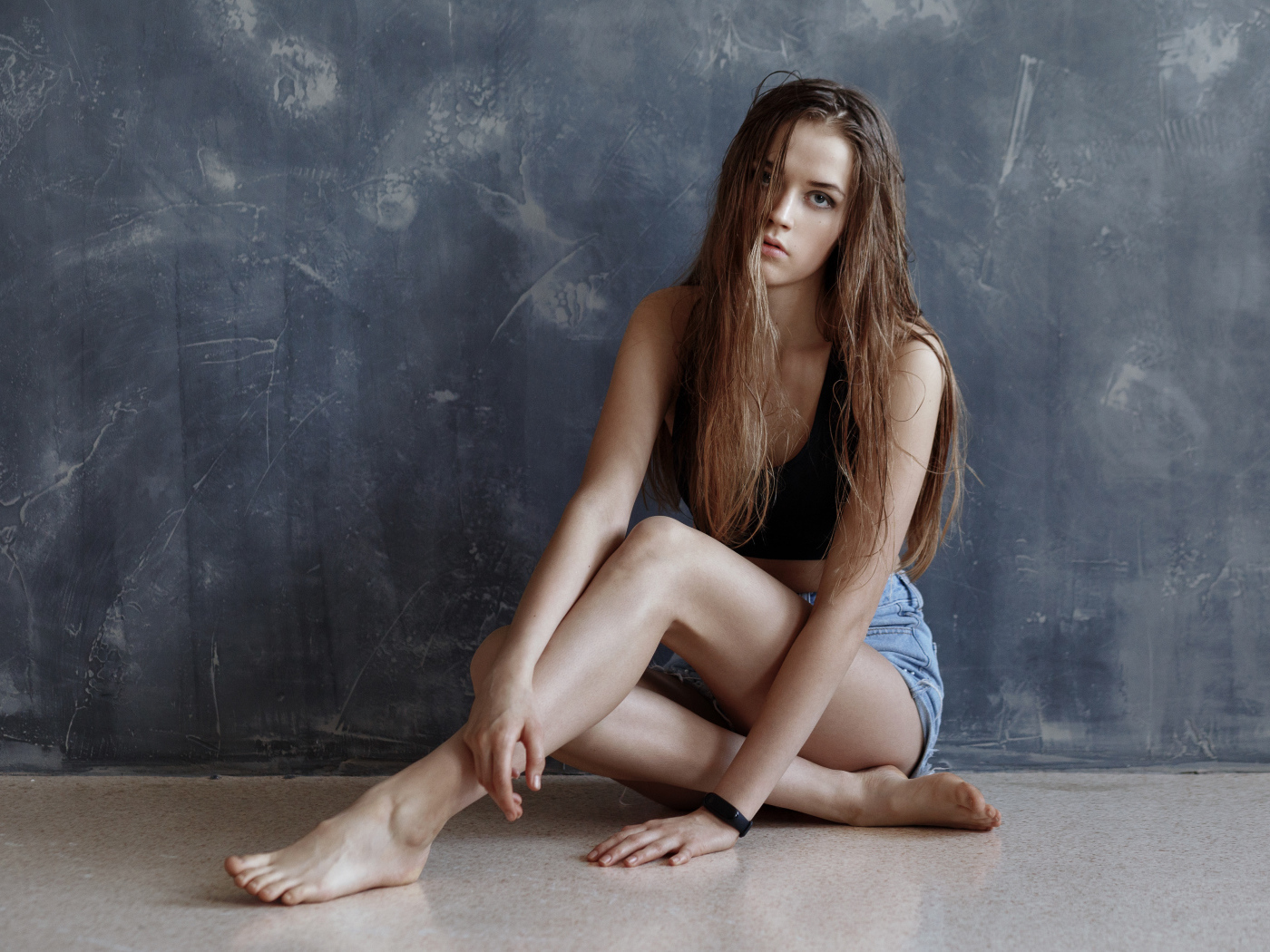 Молодая девушка с мокрыми волосами сидит у стены 