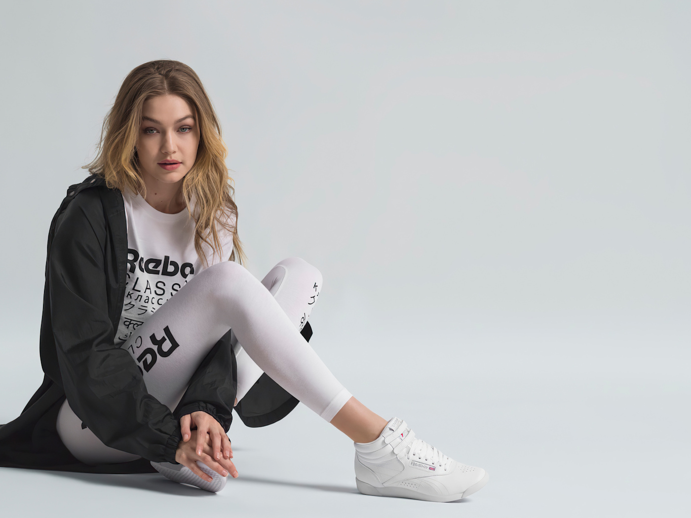 American supermodel Gigi Hadid in a tracksuit sits on the floor