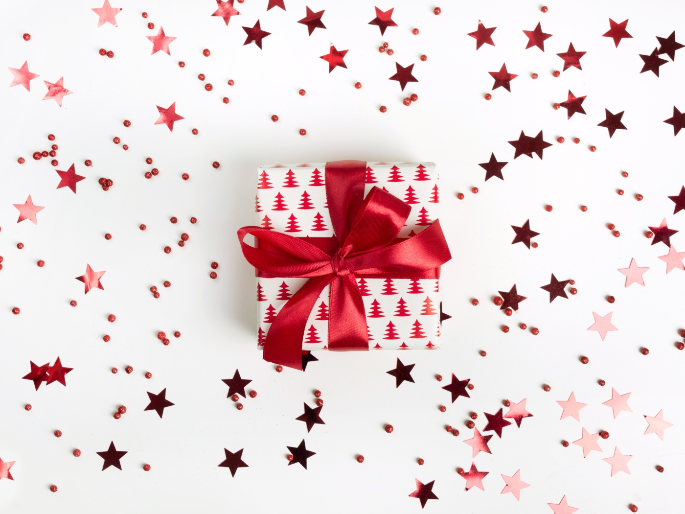 Подарок с красным бантом на белом фоне со звездочками
