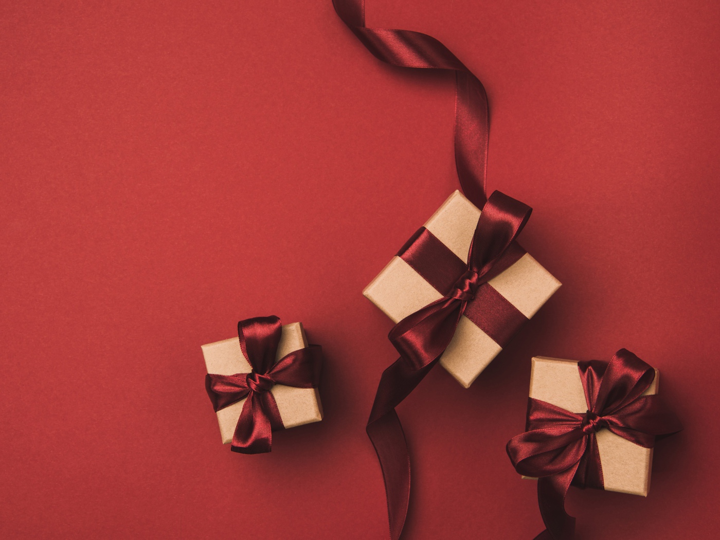 Три подарочные коробки с бантами на красном фоне
