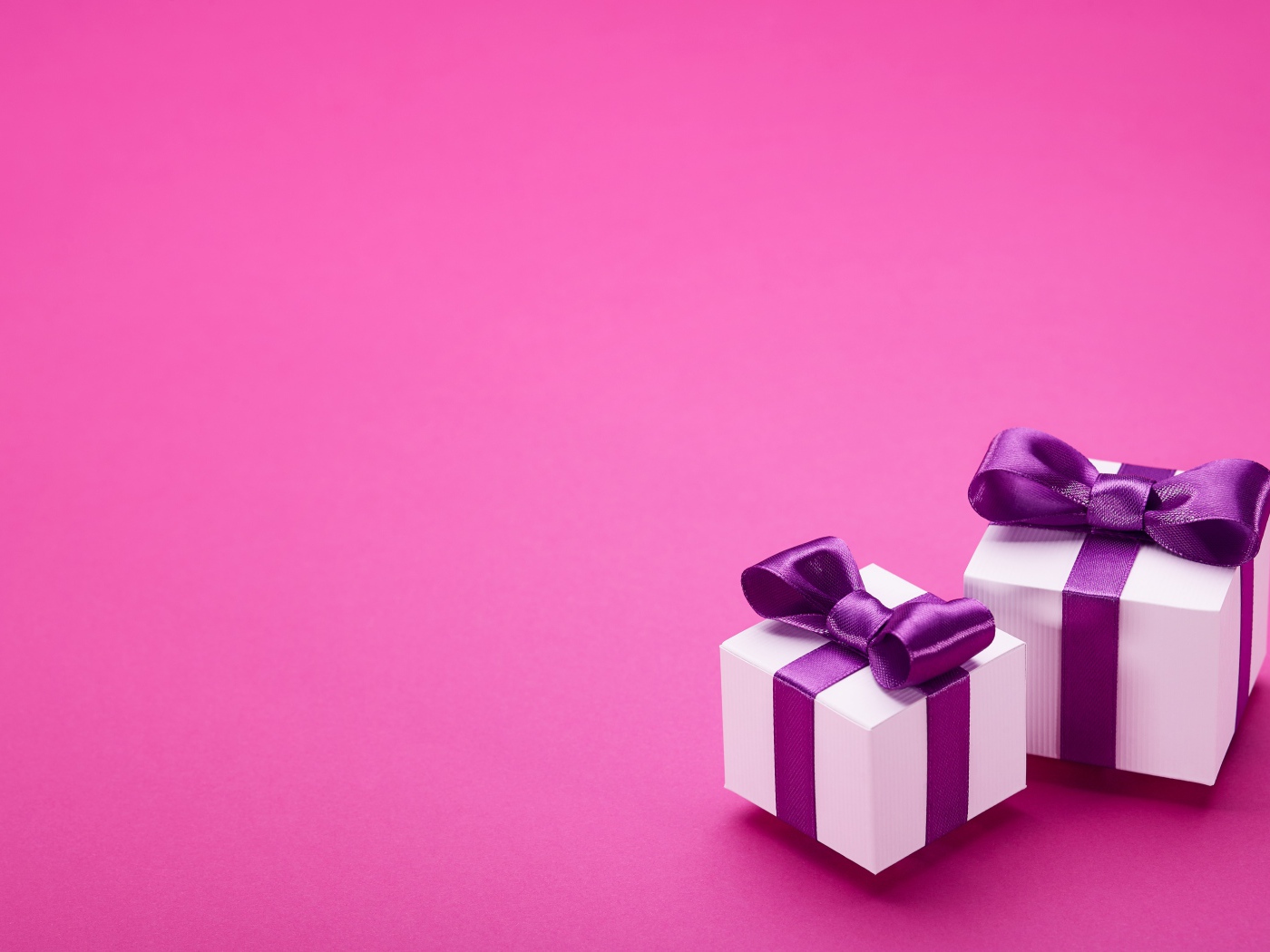 Два подарка с бантами на розовом фоне 