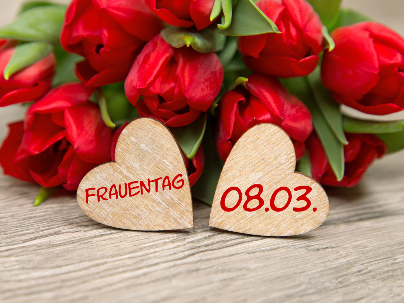 Два сердечка на столе с букетом красных тюльпанов на 8 марта 