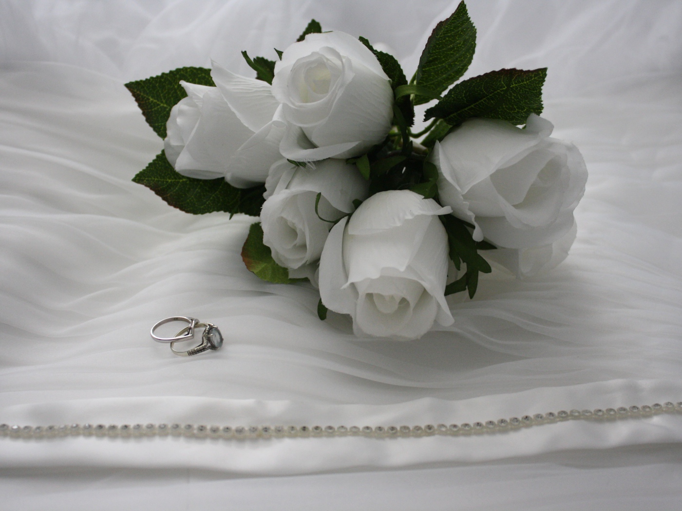 Белые бутоньерки с кольцами на белом покрывале 