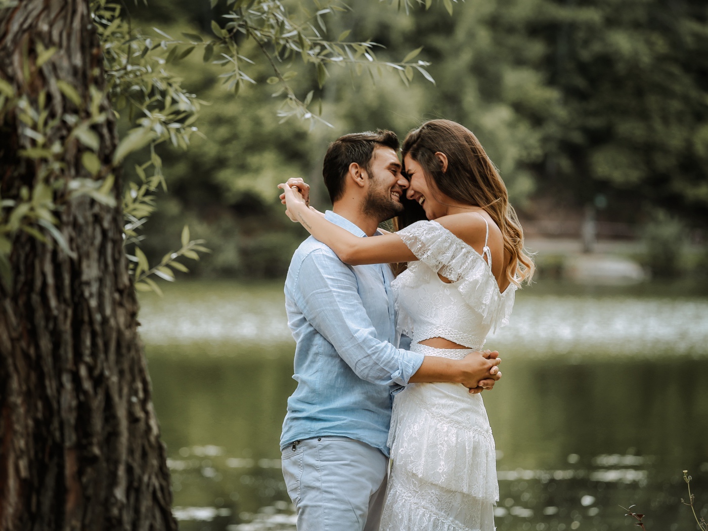 Влюбленная пара стоит у пруда в парке 