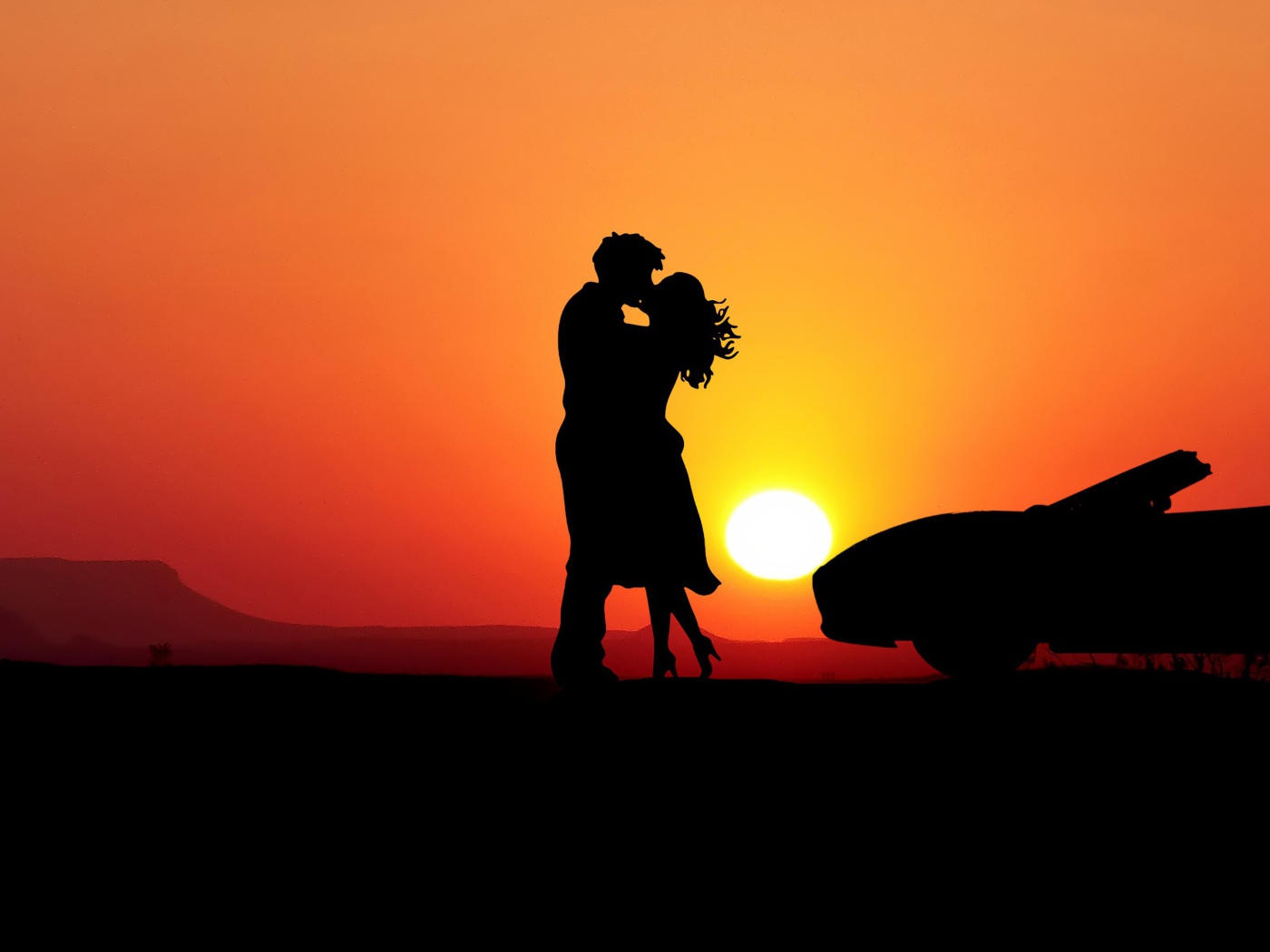 Целующаяся пара на фоне заката с автомобилем