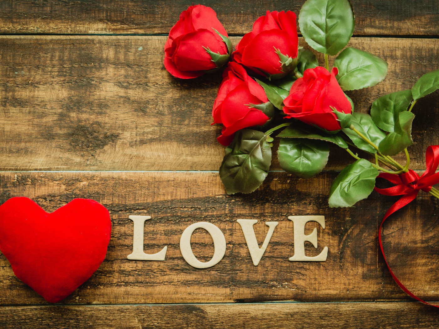 Надпись LOVE на столе с розами и красным сердцем