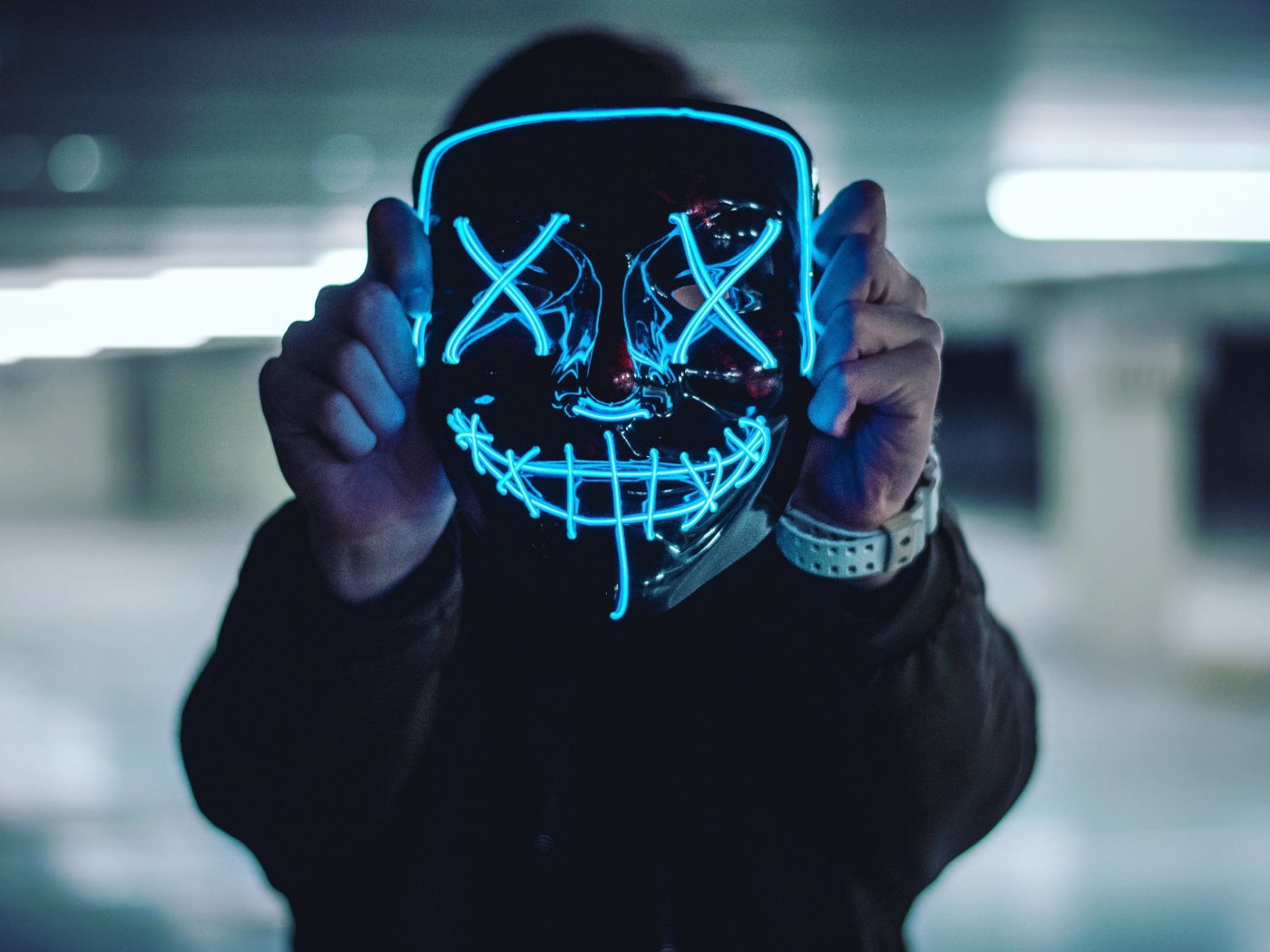 Неоновая маска анонима в руках у парня 