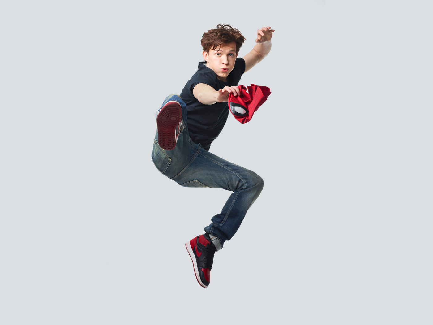 Молодой актер Том Холланд в прыжке на сером фоне