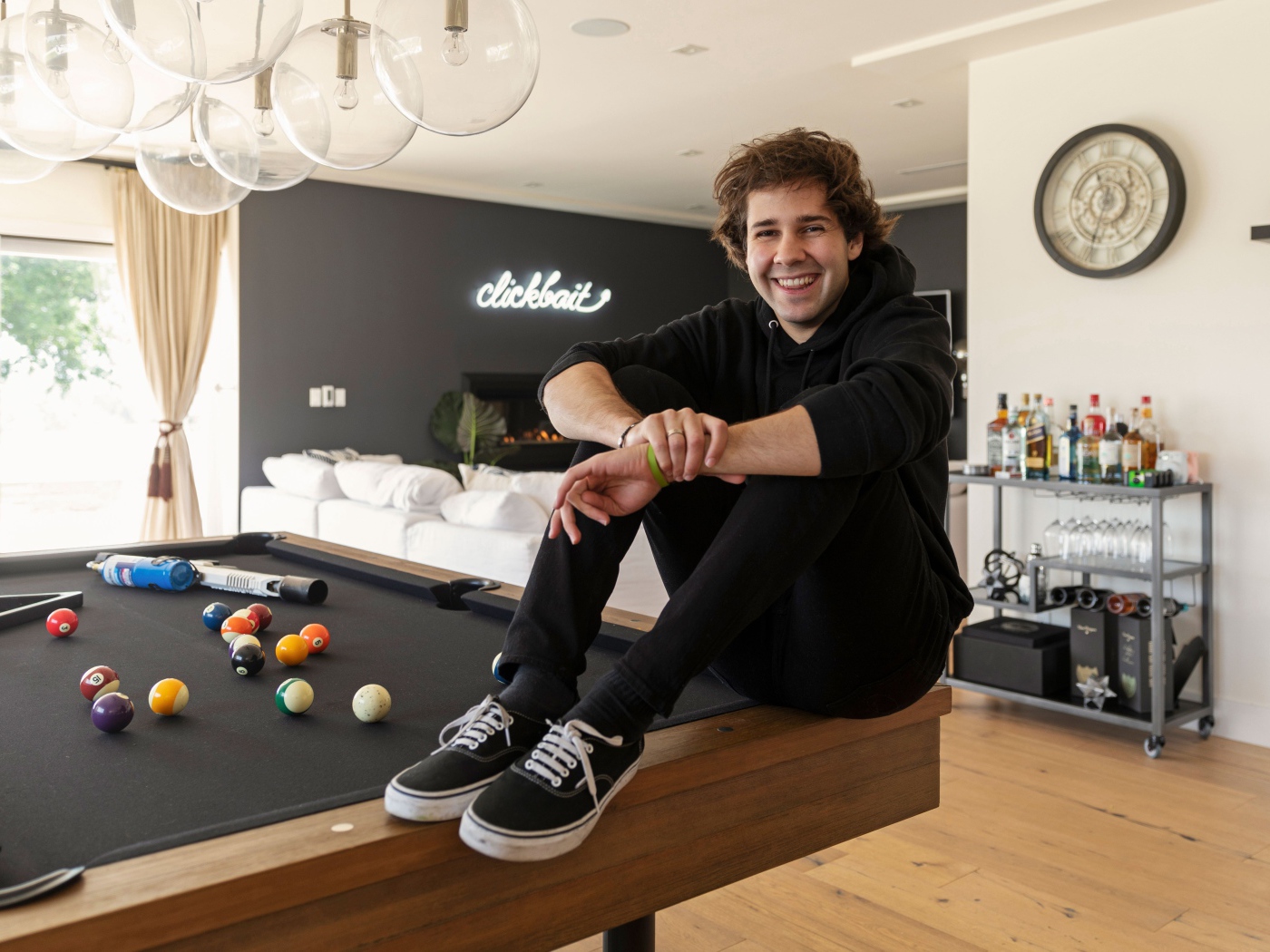 Молодой блогер, юморист  Дэвид Добрик сидит на столе