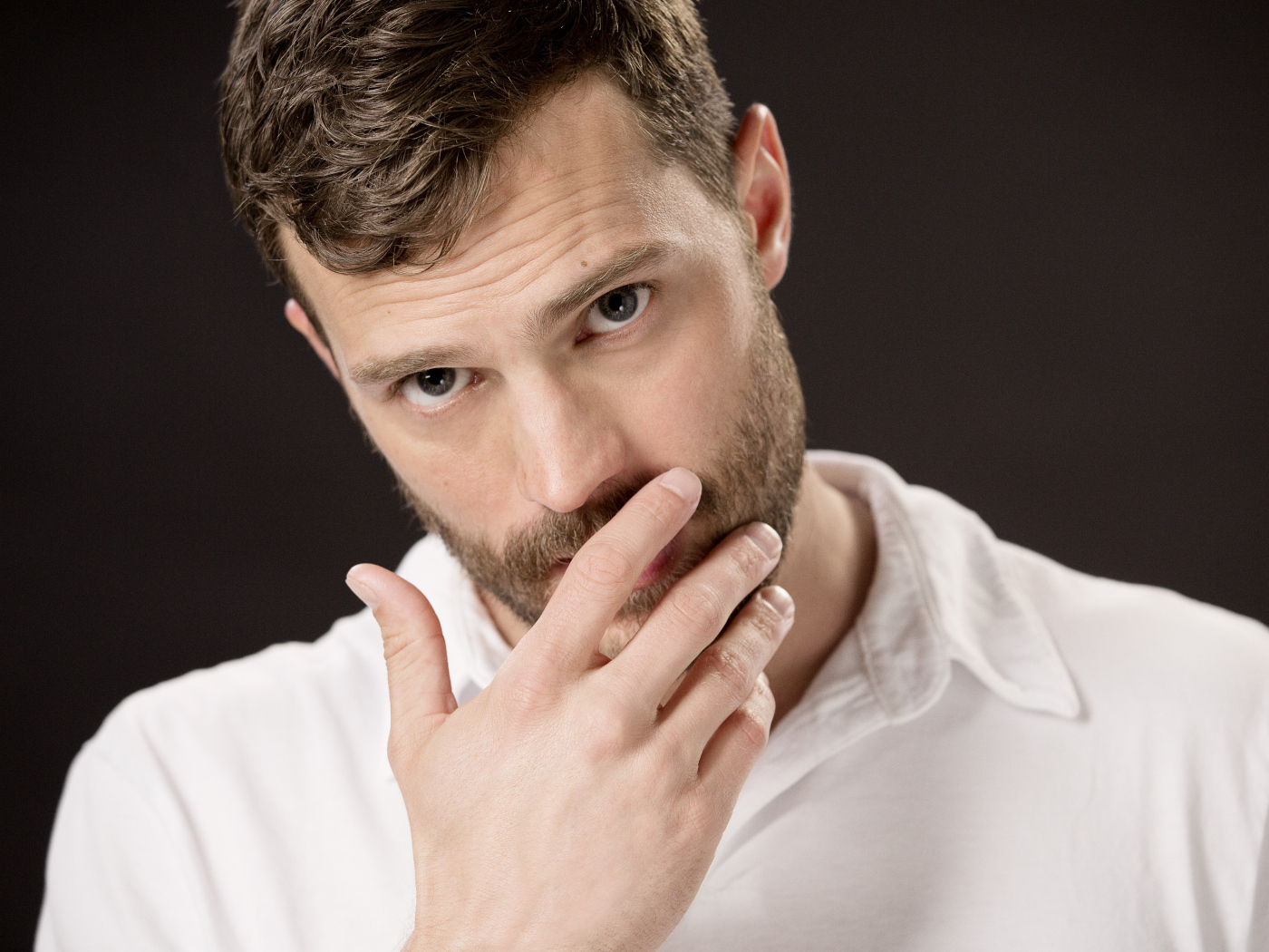 Молодой мужчина, актер Джейми Дорнан с рукой у лица