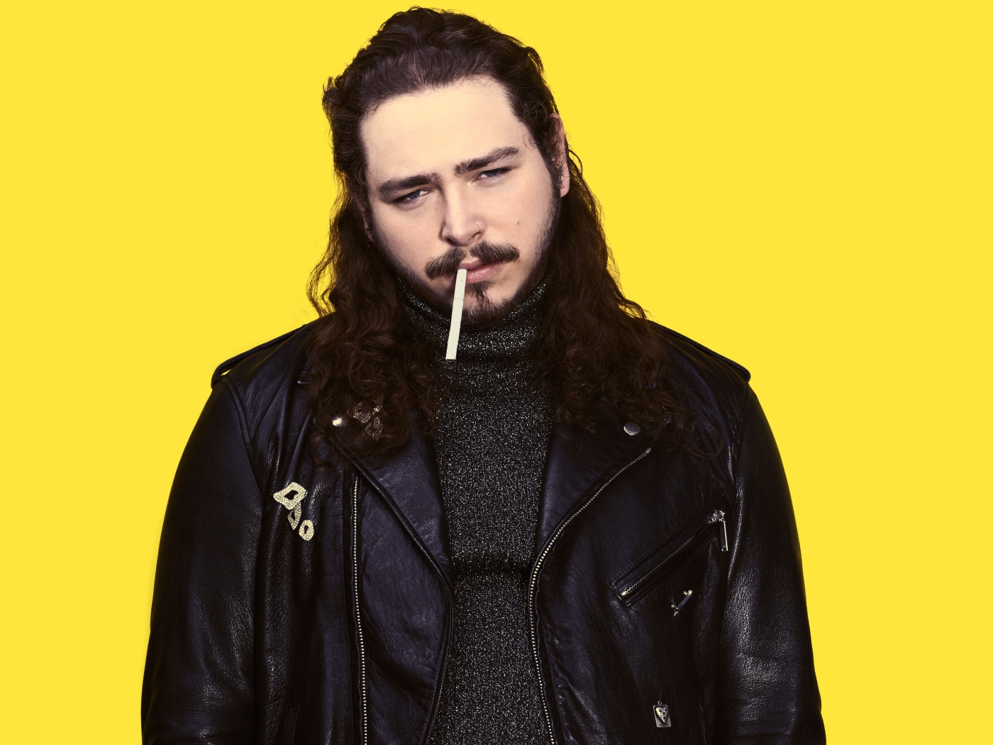 American rapper Post Malone in a black jacket on a yellow background