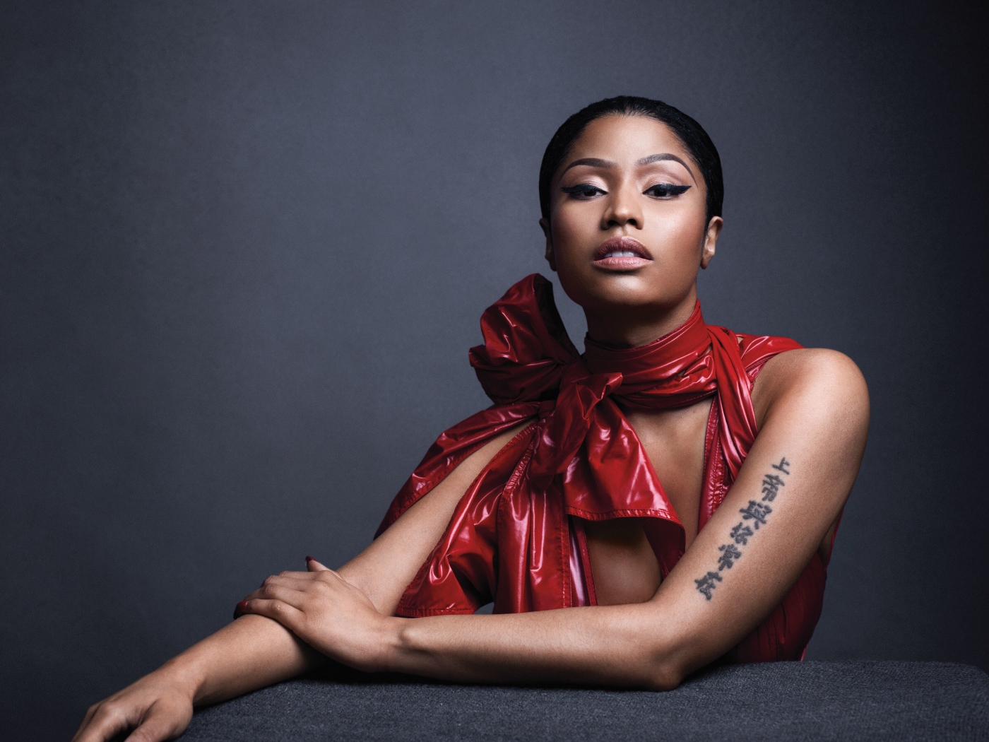 Американская певица, рэпер Ники Минаж  в красном наряде на сером фоне