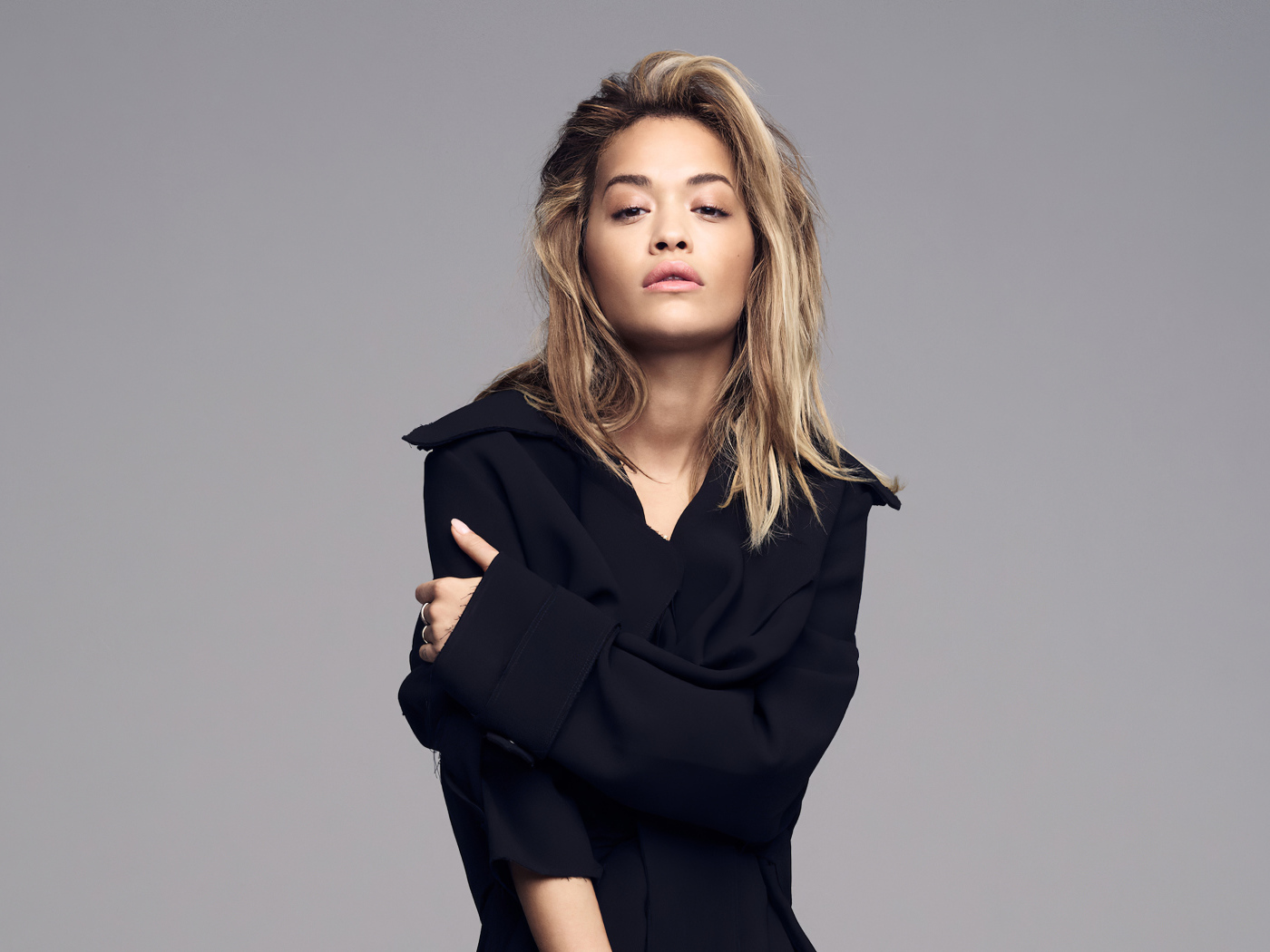 Singer Rita Ora in a black outfit on a gray background
