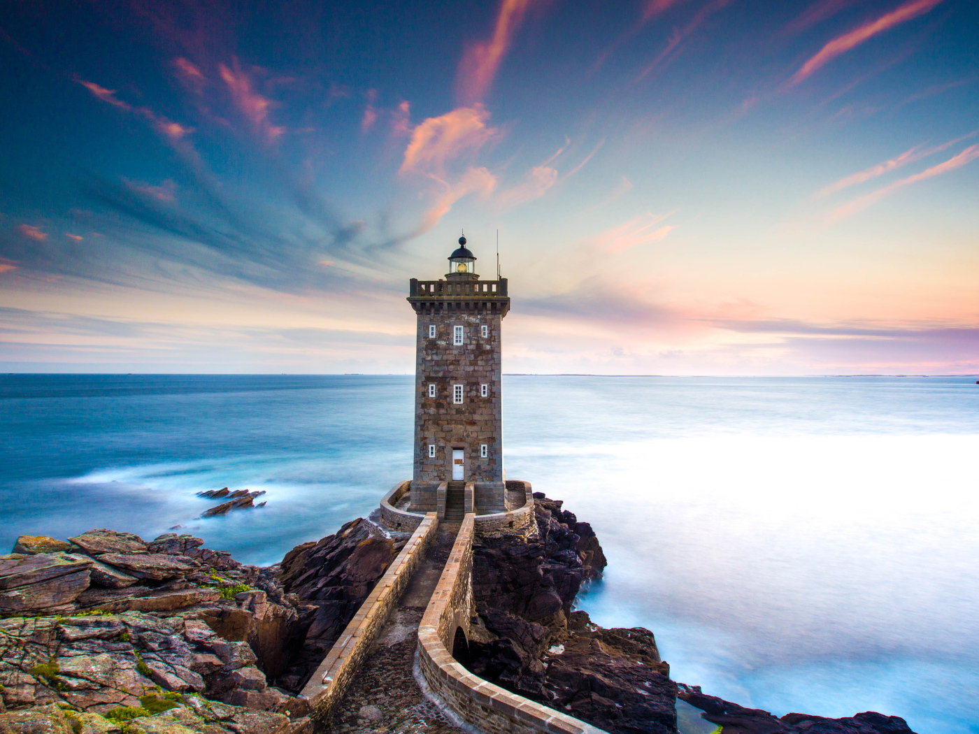 Большой маяк на фоне неба на берегу утеса 