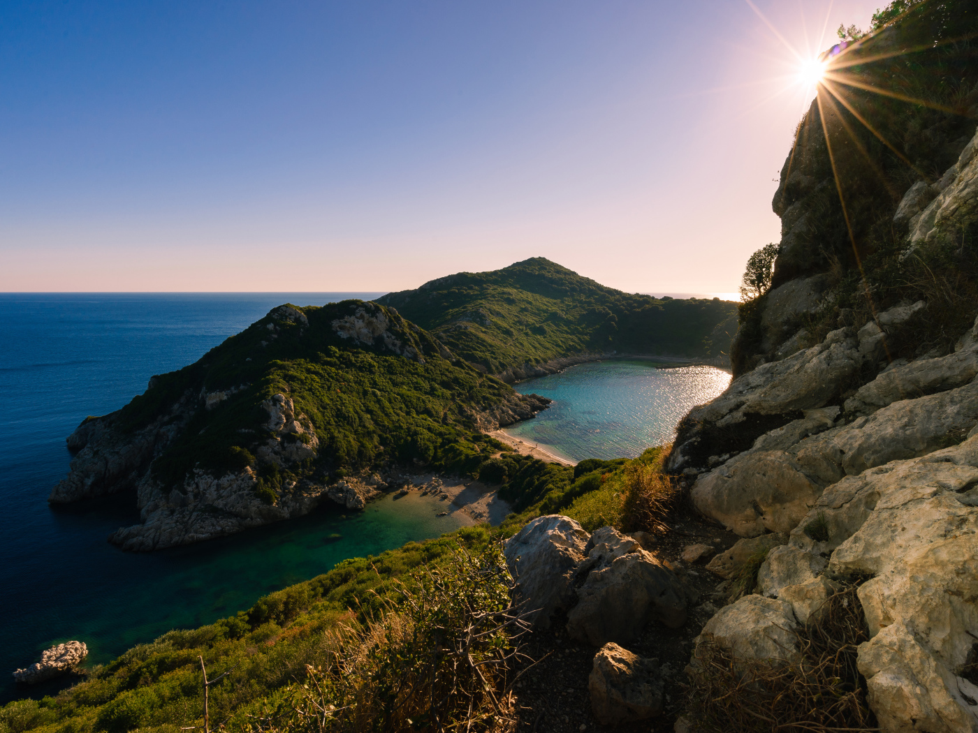 Яркое солнце за скалой у тихого моря