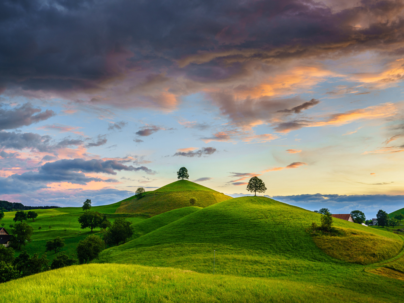 Зеленые холмы с деревьями под небом с грозовыми облаками