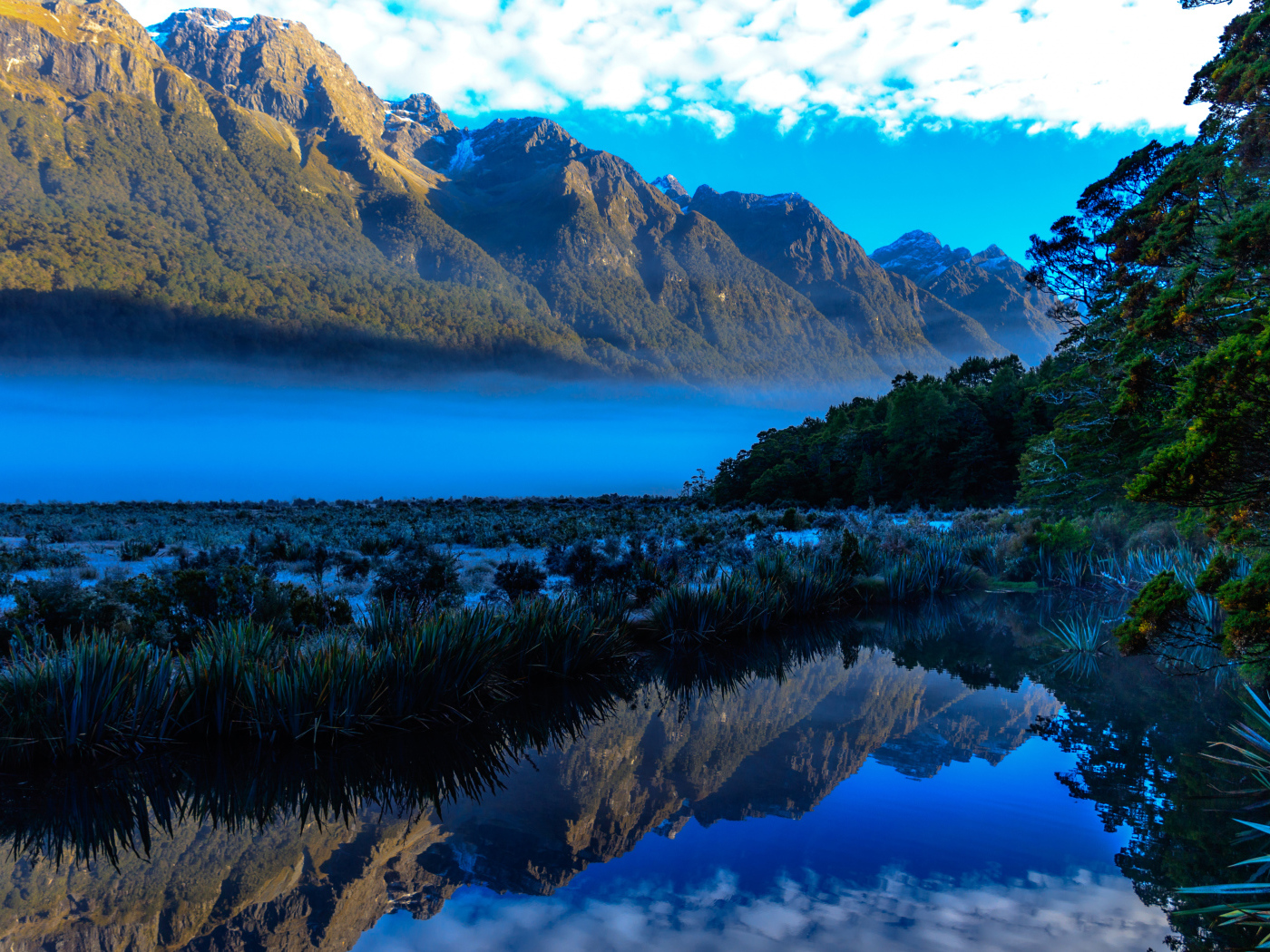 Горы и небо отражаются в голубой воде озера 