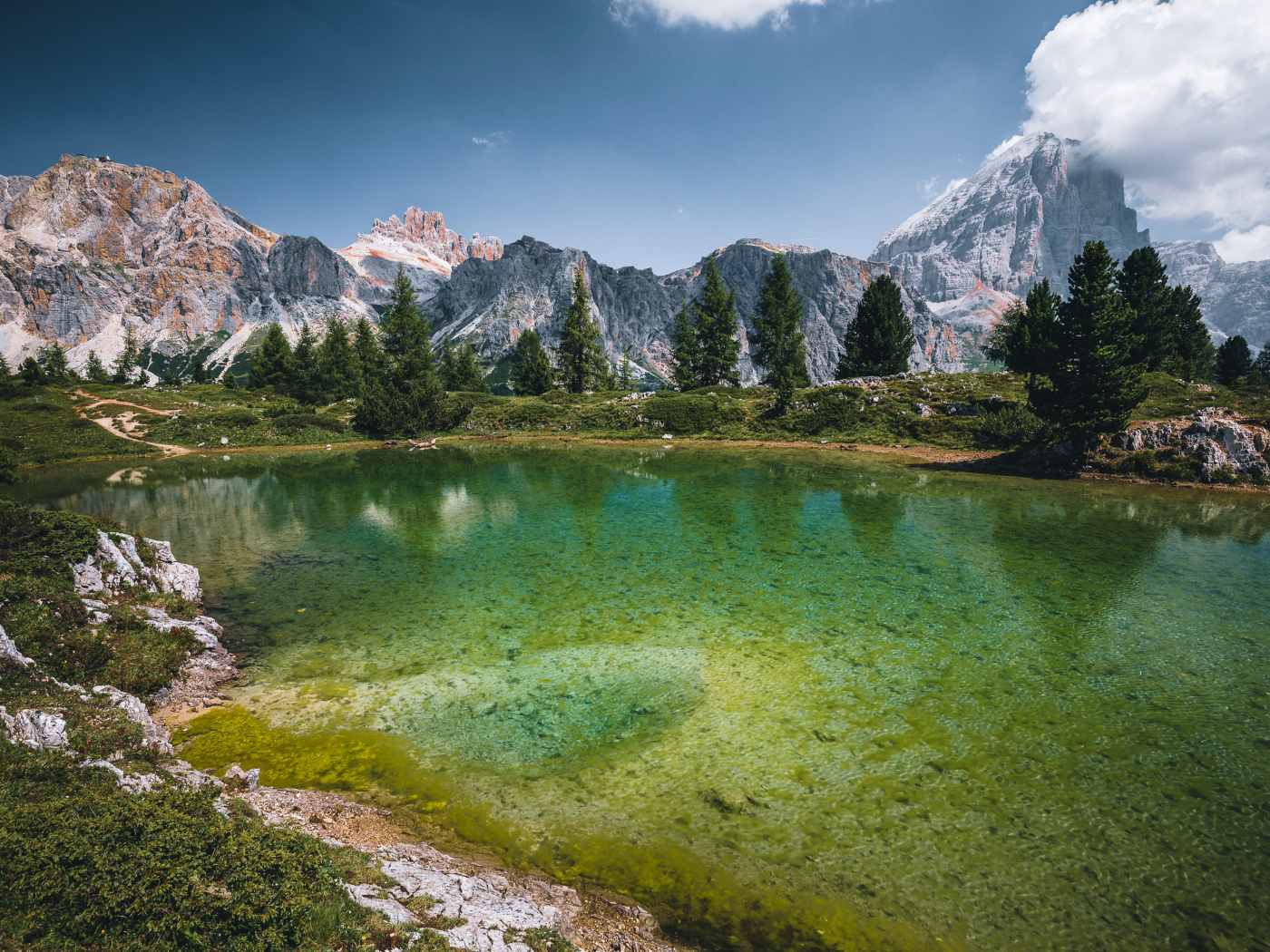 Озеро у заснеженных гор под небом с белыми облаками