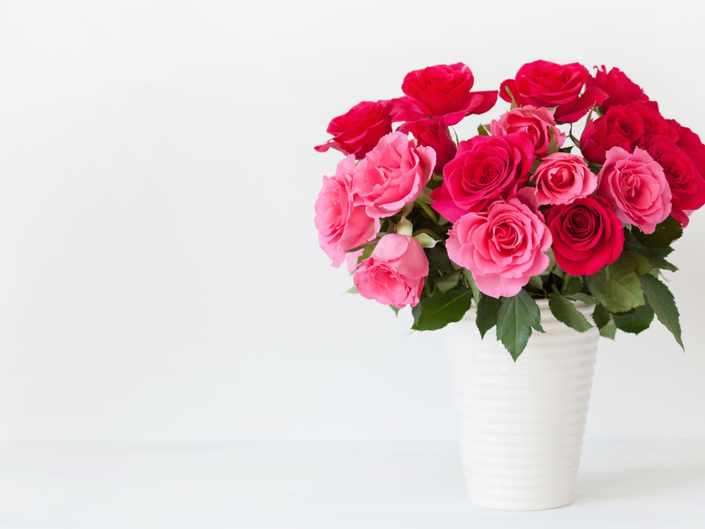 Букет красивых розовых роз в белой вазе на белом фоне