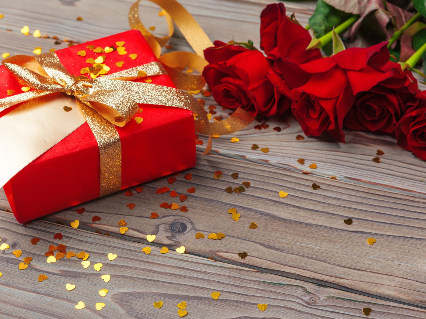 Букет красный роз с большим подарком на столе