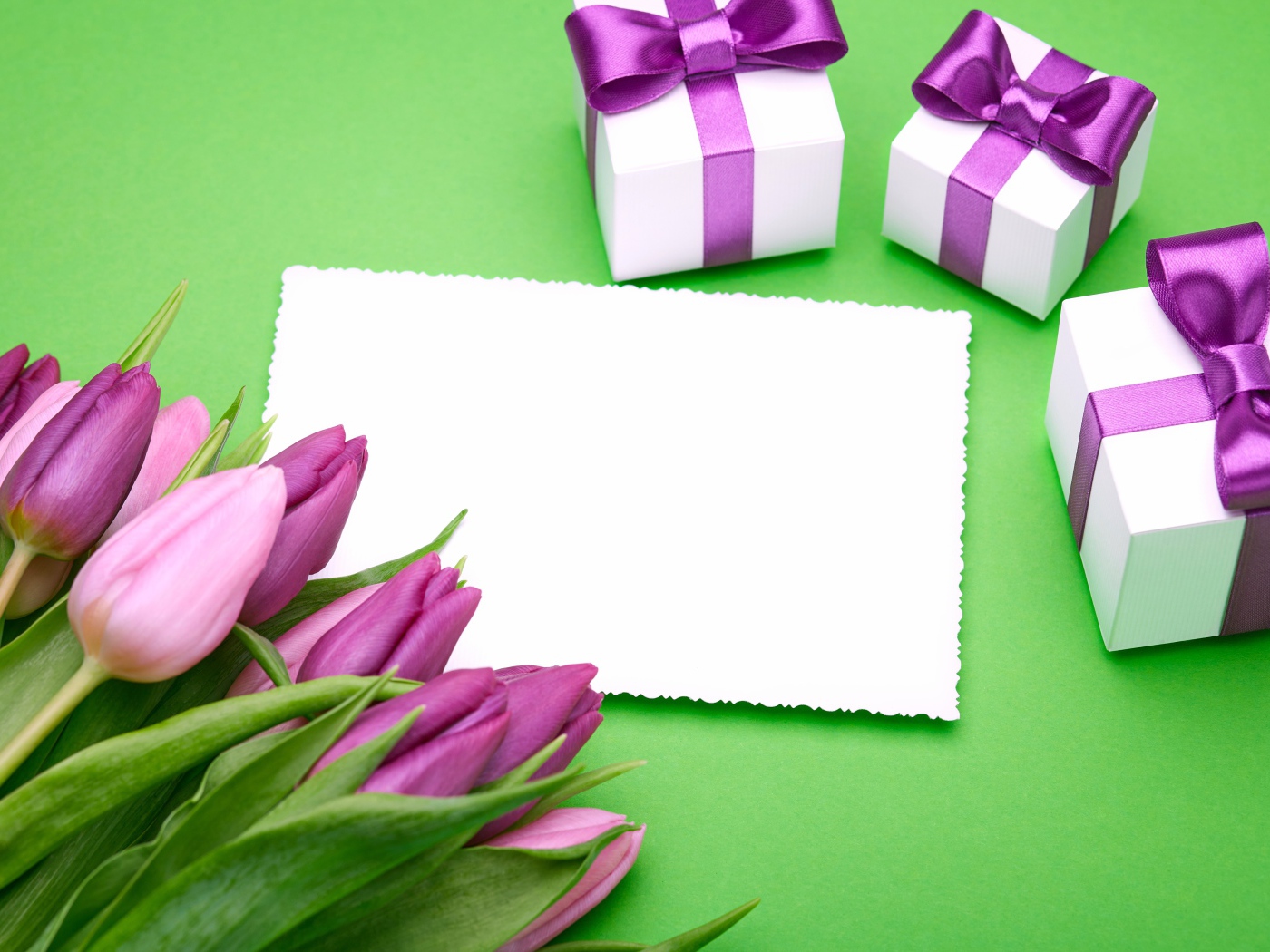 Букет тюльпанов на столе с листом бумаги и подарками 