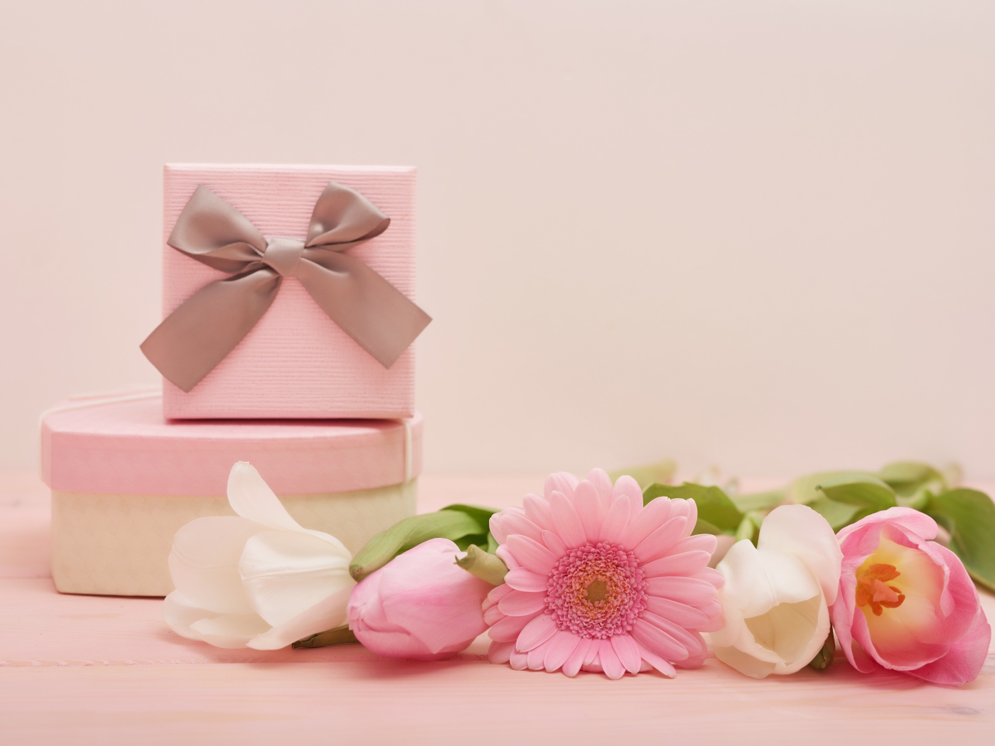 Букет тюльпанов с герберой на столе с подарками