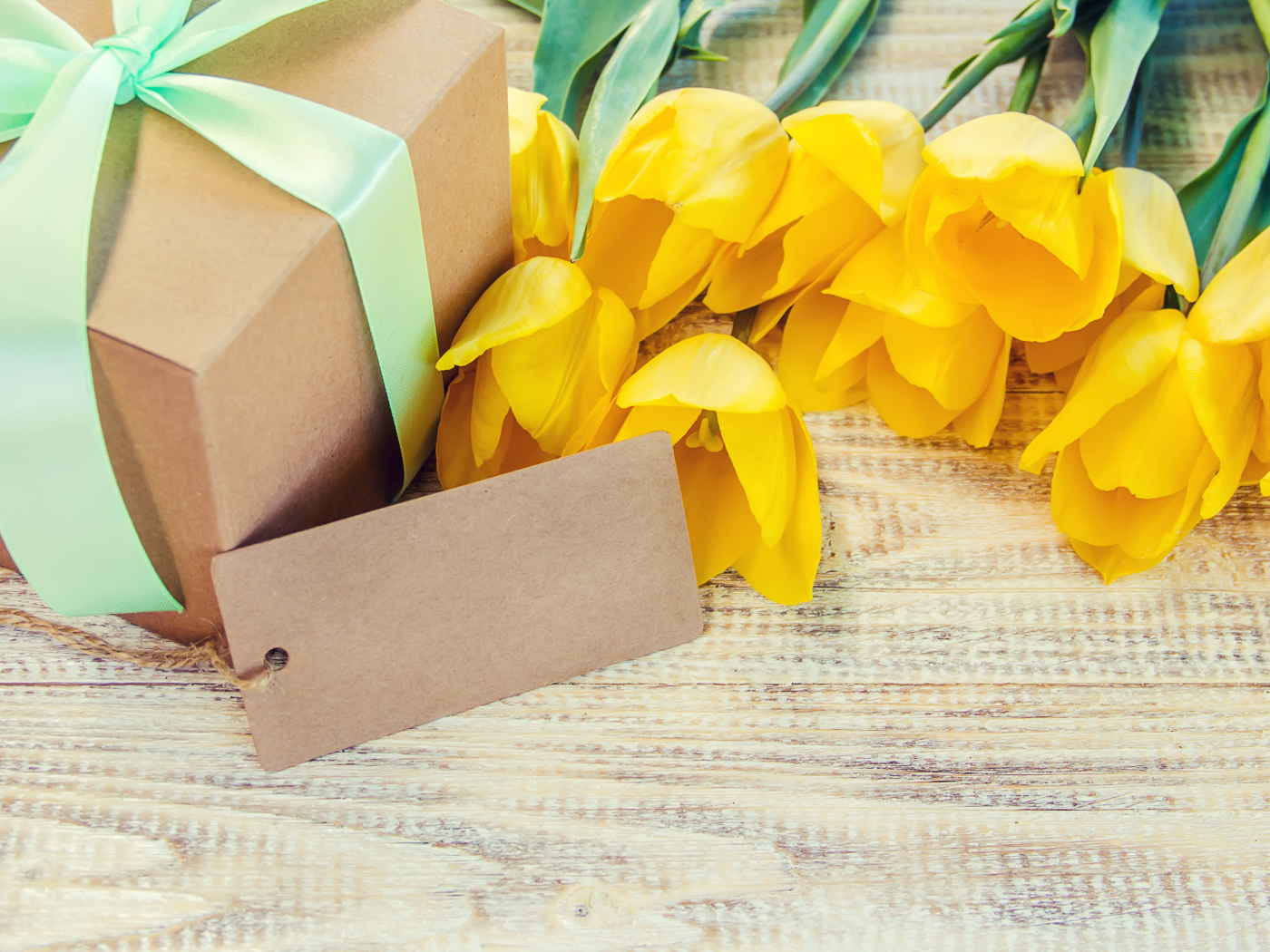 Букет желтых тюльпанов с подарком на столе 