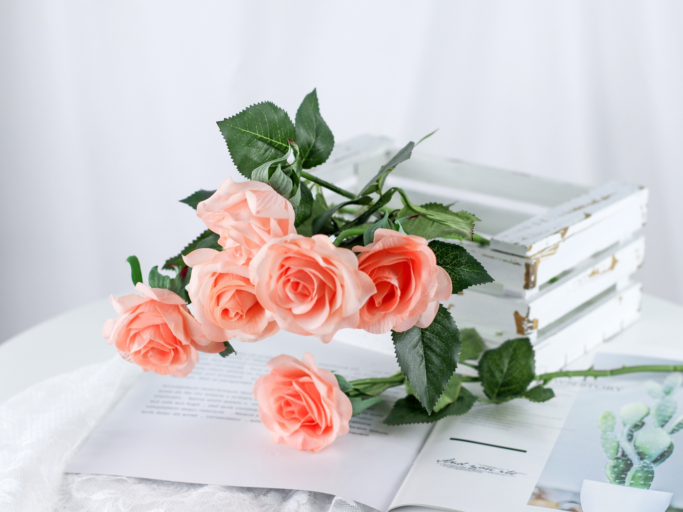 Розовые цветы лежат на столе на журнале