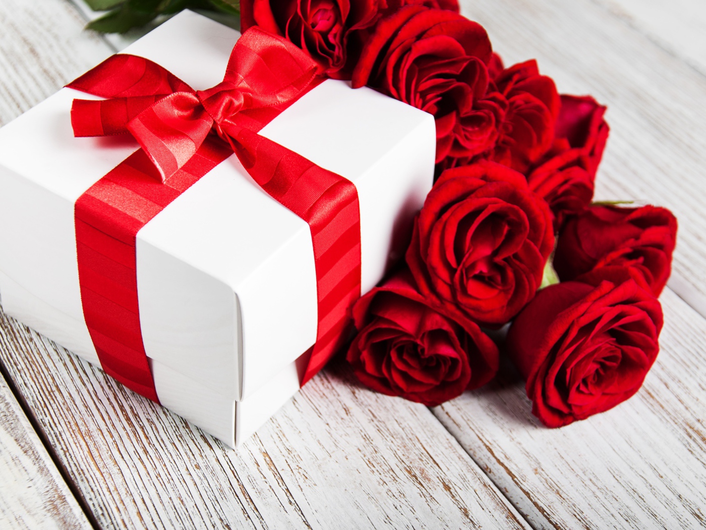 Красные розы на столе с подарком с красной лентой