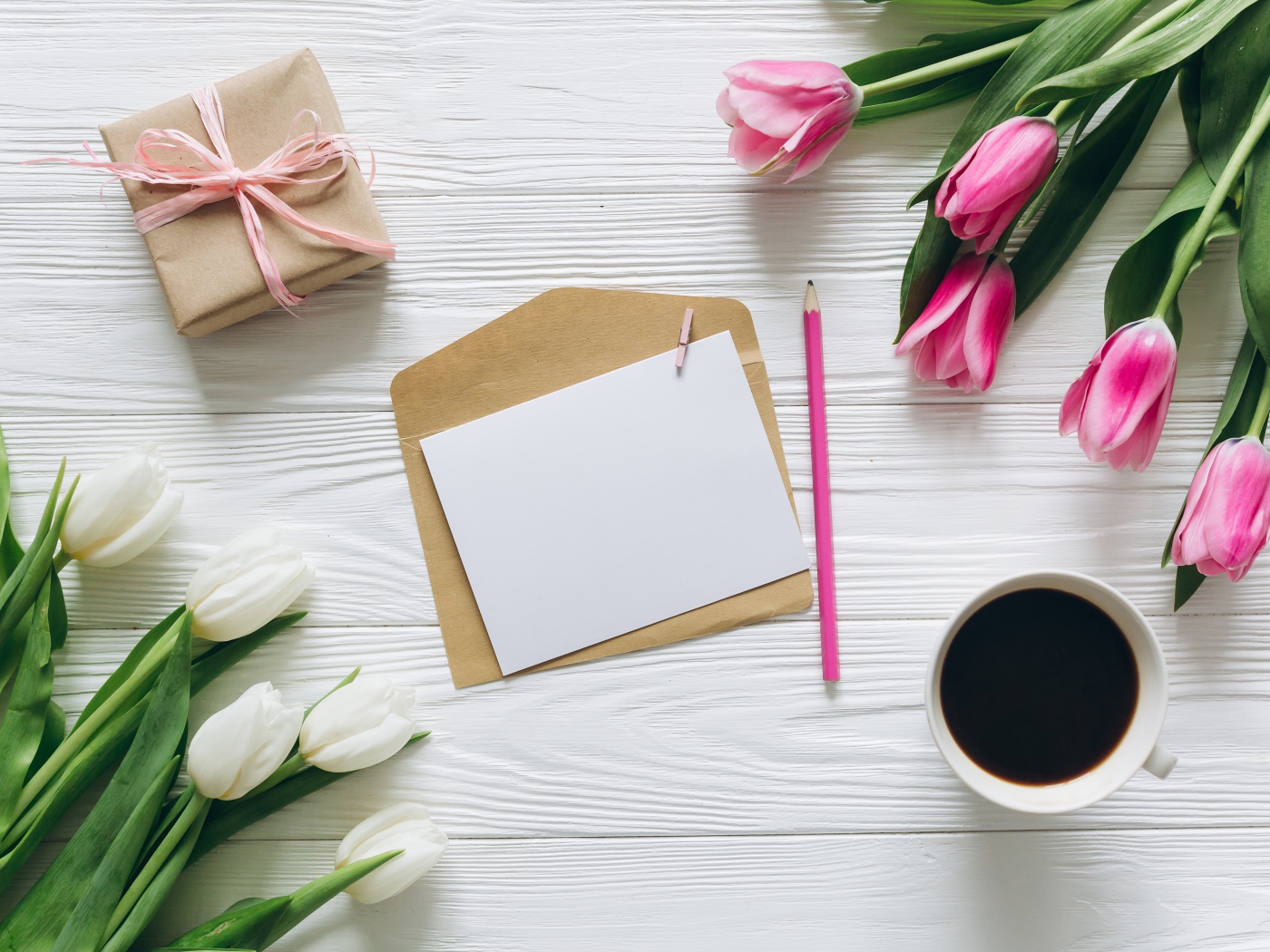 Два букета тюльпанов на столе с подарком, кофе и письмом