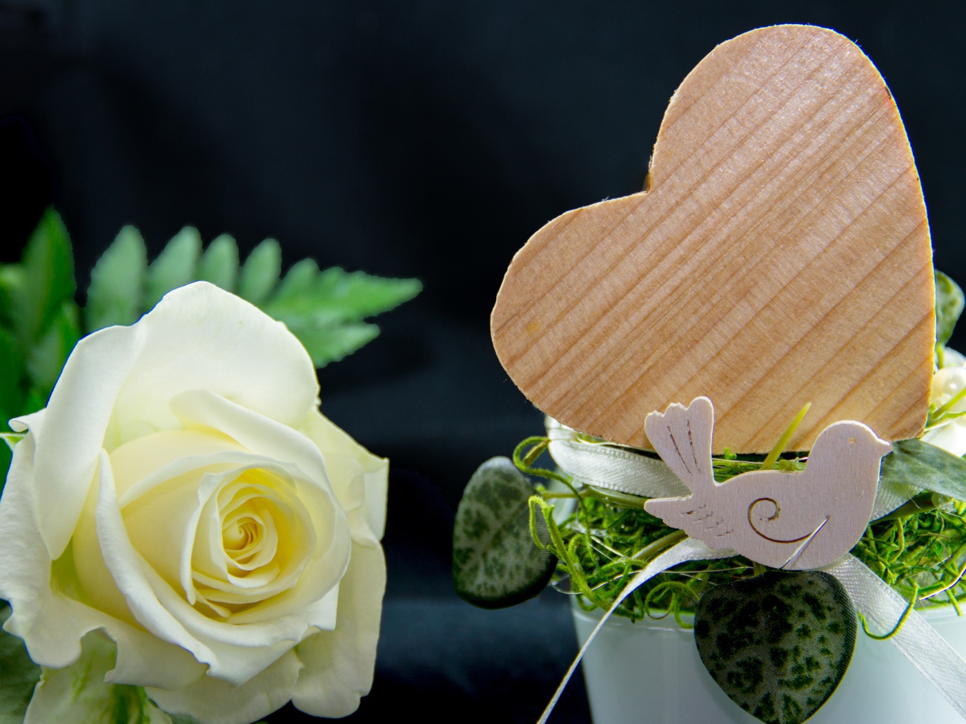 Деревянное сердце и белая роза на столе 